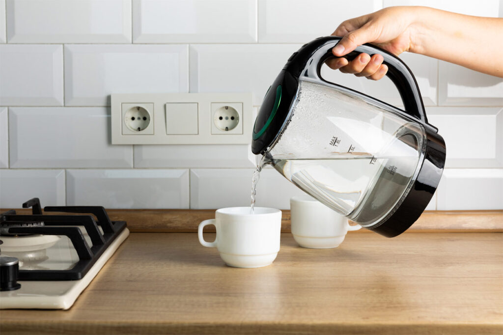 Gekochtes Wasser aus dem Wasserkocher in eine Tasse gießen.